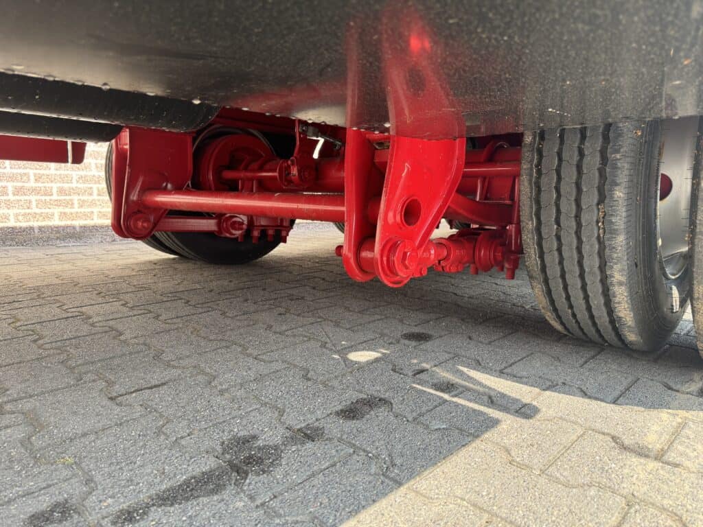 Keurig onderhouden onderstel van lasauto met rode onderdelen en grote banden, klaar voor professioneel gebruik.