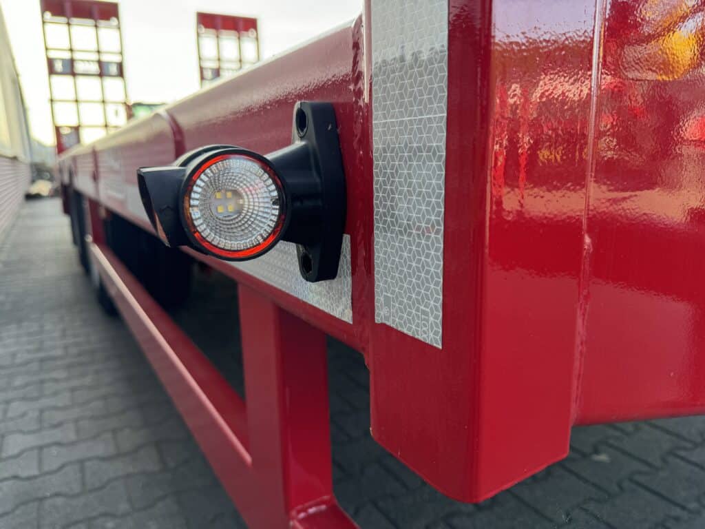 Verlichtingseinheid op vrachtwagen met reflecterende dekking en opvallende rood-witte kleur.
