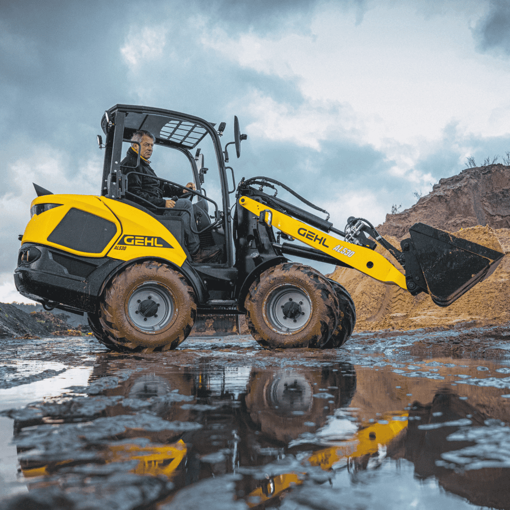 1. Geel geleide shovel op bouwplaats met water en modder, industriële omgeving.