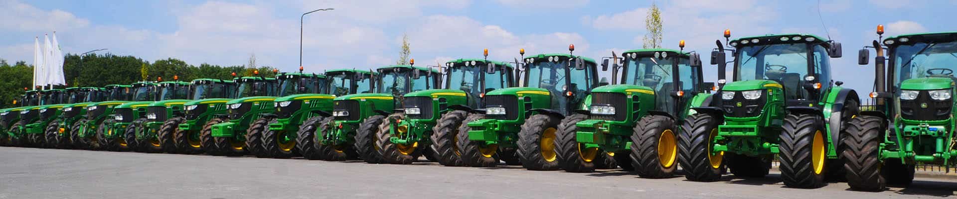 Grote lijn met groene tractoren van Geert-Jan de Kok B.V. op een open terrein.
