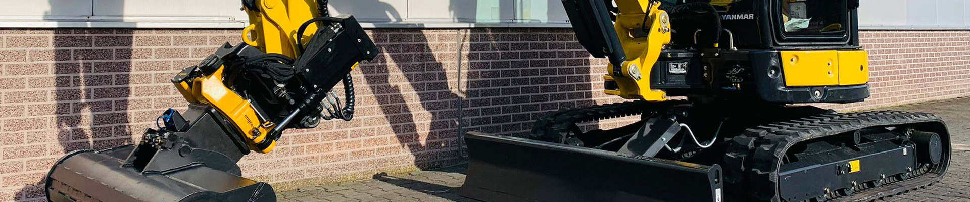 Kleingebouwd graafmachine en constructionvoertuig op oprit met bak en rupsen.