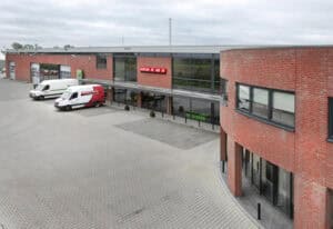 Modern bedrijfsgebouw van Geert-Jan de Kok B.V. met parkeergelegenheid en bedrijfsvoertuigen.