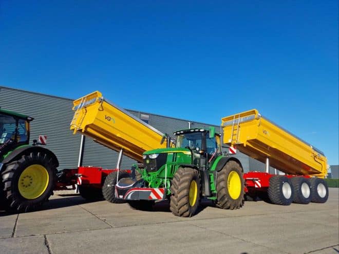 Zware landbouwtractor met gele onderwagens en remorques, klaar voor oogst of landbouwwerkzaamheden.