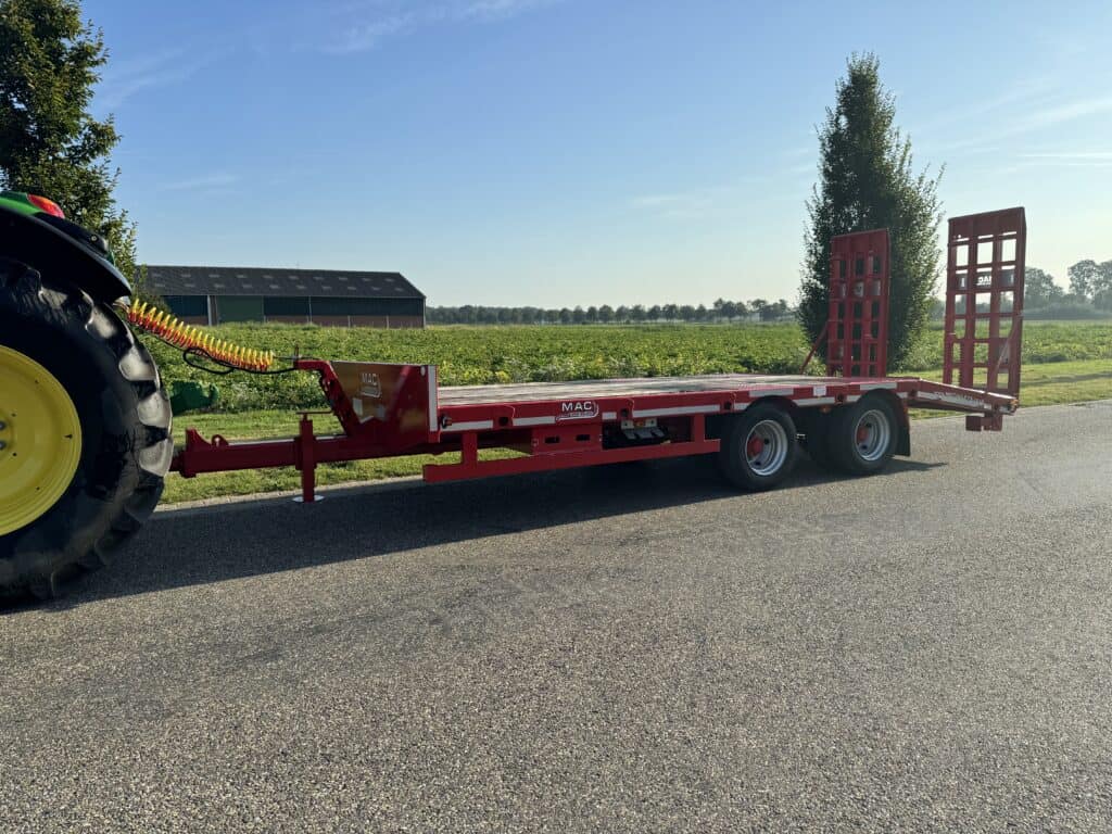- Uitgebreid landbouwtransport met rode trailer en tractor op het platteland.