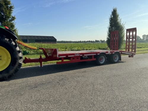 - Uitgebreid landbouwtransport met rode trailer en tractor op het platteland.