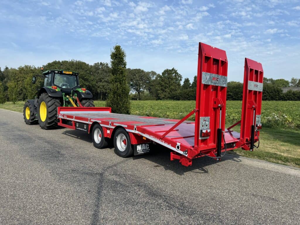 Betonploeg voor landbouw en bouw, getrokken door tractor op landelijke weg.