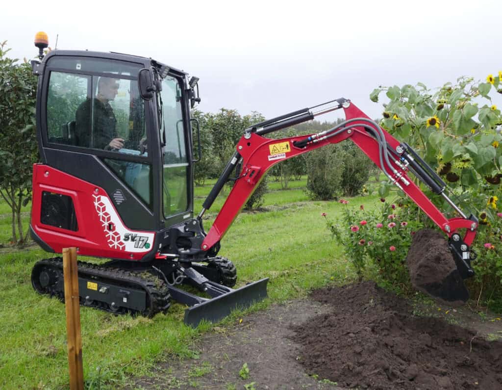 Compacte minikraan in tuinbouwlandschap, perfect voor kleine grondwerken en tuinontwerp.