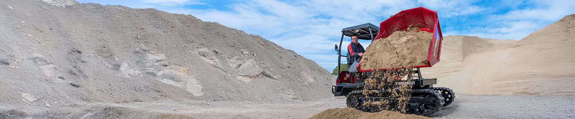 Mini graafmachine met laadbak in een zand- en grindgroeve.