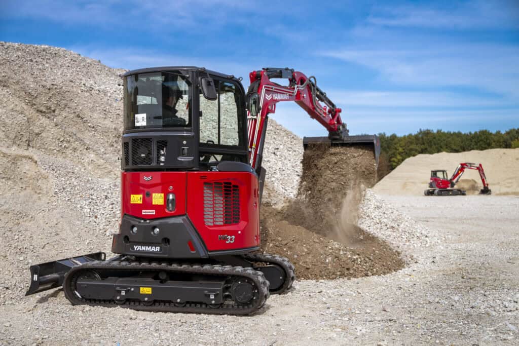 Kleine graafmachine van Yanmar bij bouwplaats, aarde bergt en verplaatst grond.