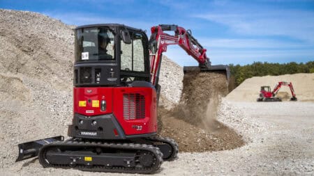 Kleine graafmachine van Yanmar bij bouwplaats, aarde bergt en verplaatst grond.