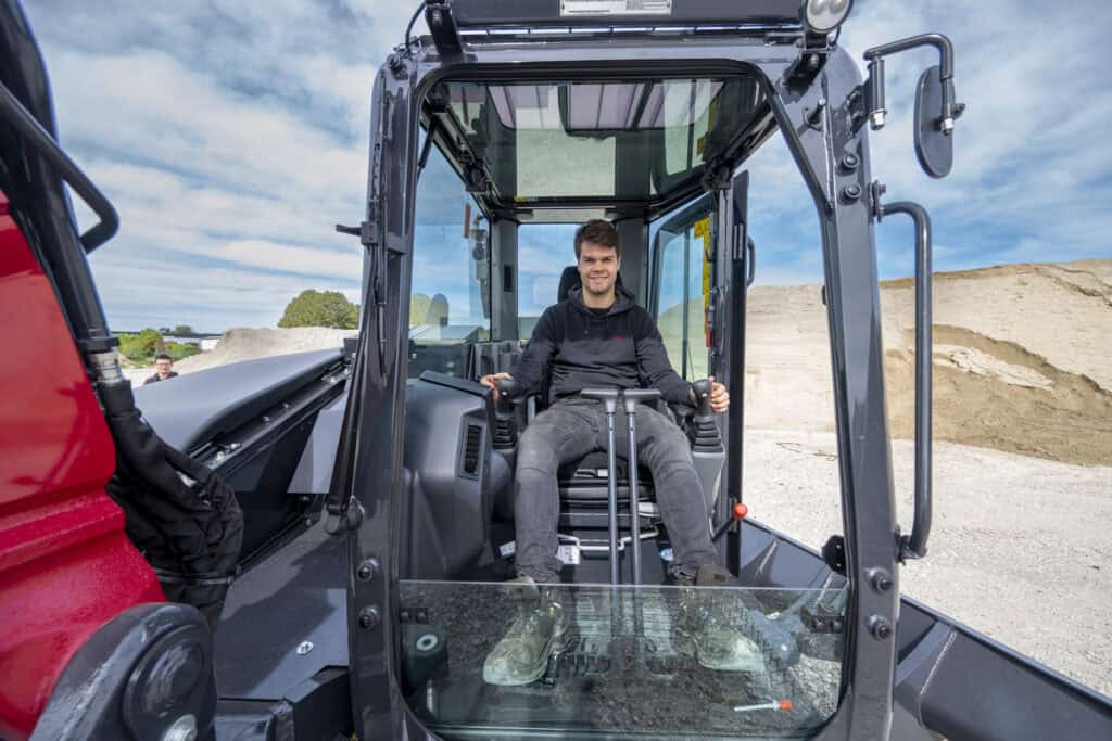 Veilig en modern bouwmaterieel, werknemer bedient onderhoudsvriendelijke tractor.