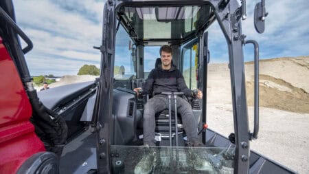 Veilig en modern bouwmaterieel, werknemer bedient onderhoudsvriendelijke tractor.
