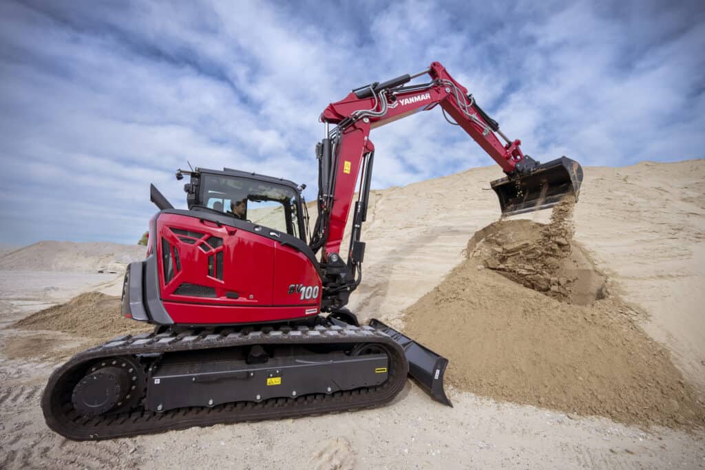 Klein bouwmachine graaft zand op een bouwplaats.