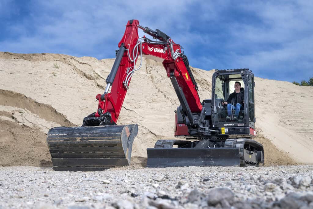 - Compacte Yanmar graafmachine op een bouwplaats in de natuur.