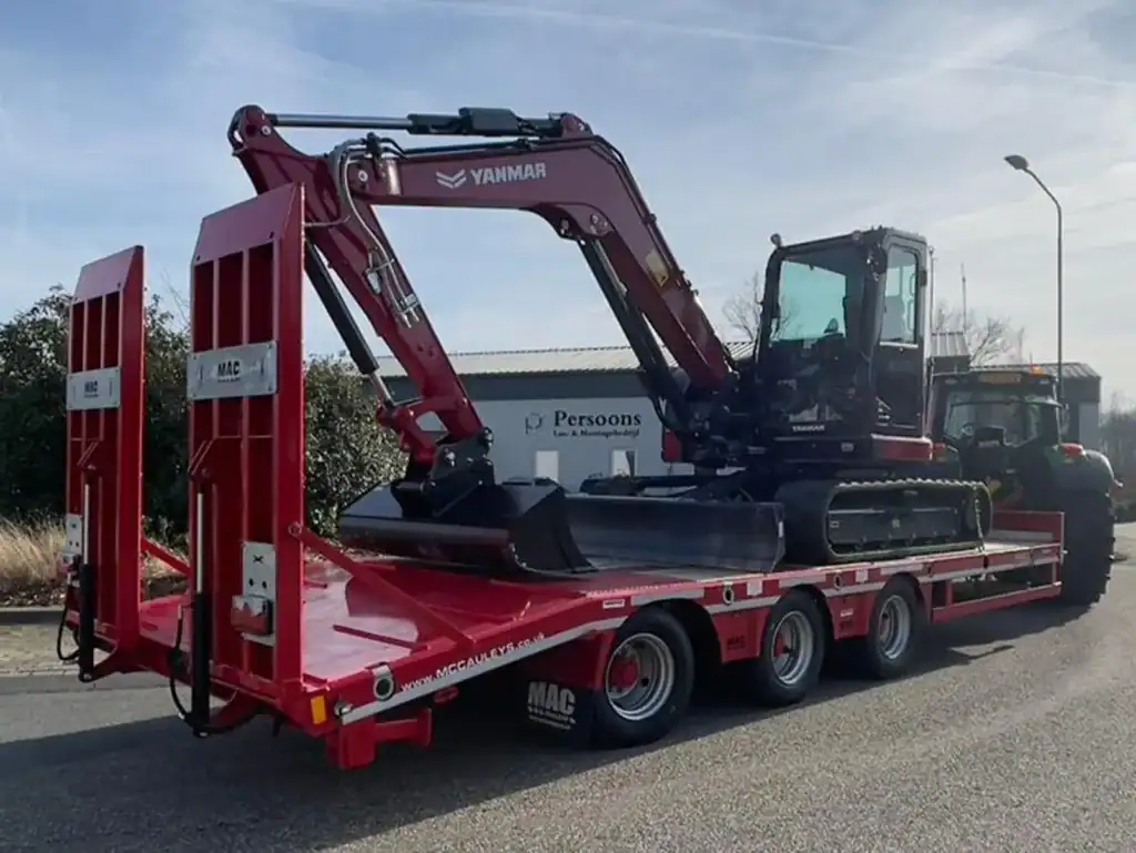 Zwaar bouwmaterieel op transportwagen klaar voor levering.