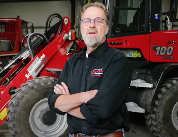 Verzekerde agrarisch technicus met tractor op werkplaats, professioneel en betrouwbaar.