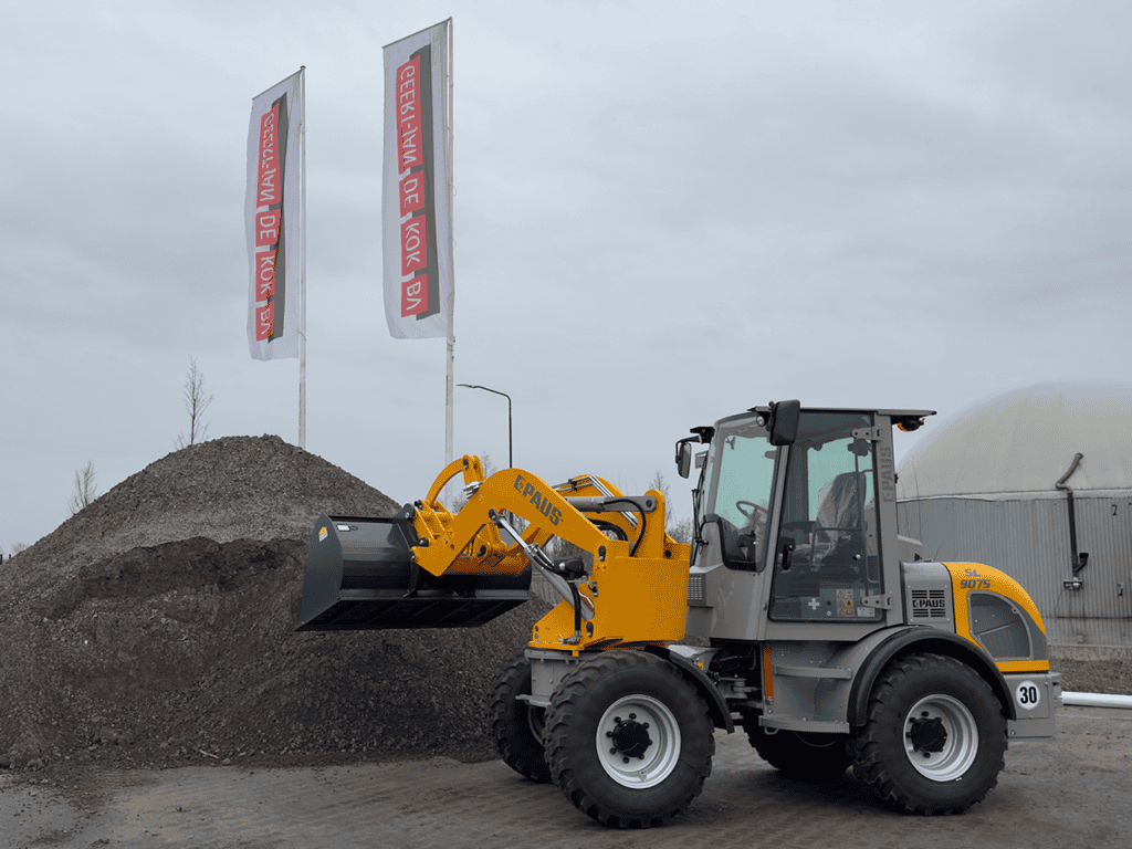 Klepelaar op bouwplaats met gravende machine voor grondverzet en aannemerswerkzaamheden.