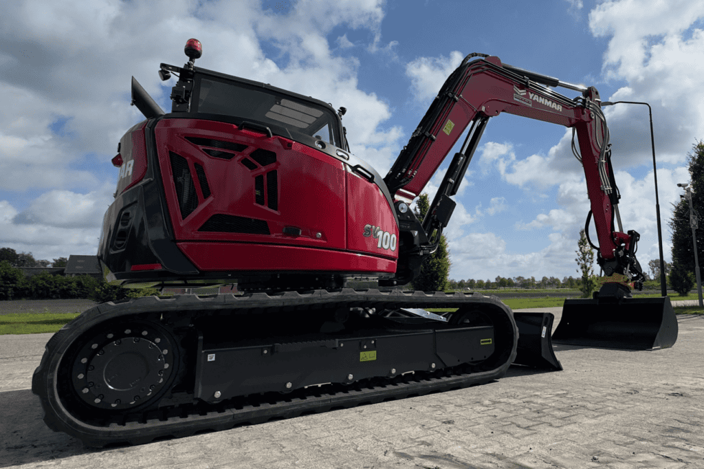 Klein gereedschap en zware bouwmachines, inclusief een graafmachine van Yanmar, op een bouwterrein.