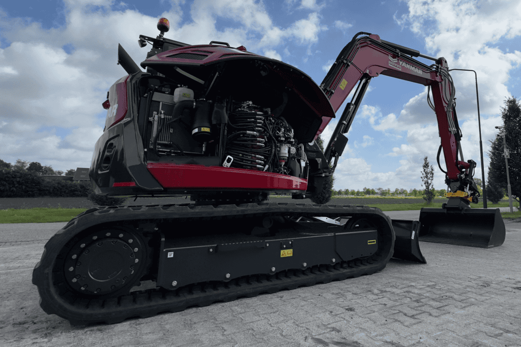 Compacte graafmachine met open motorruimte en rubberen rupsen voor bouw- en tuinwerkzaamheden.