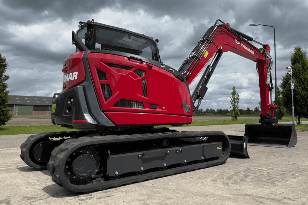Kleiboer Yanmar minigraver op bouwterrein met grijze wolkenlucht.