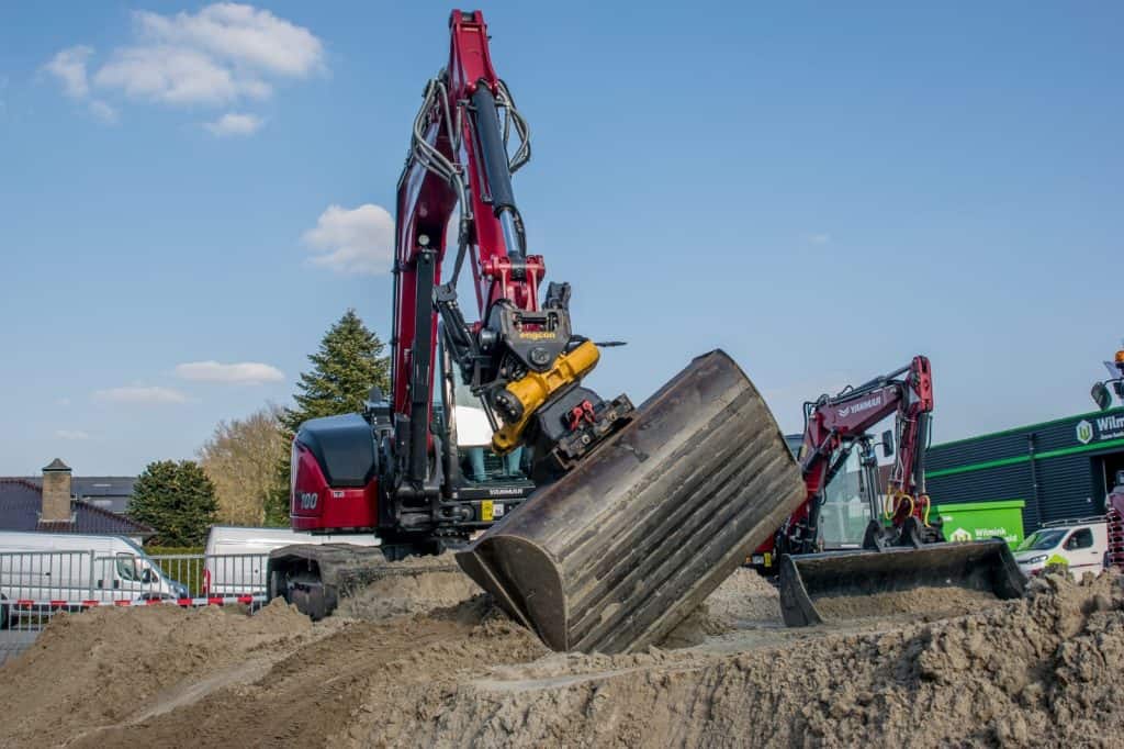Kleine graafmachines op bouwplaats met zand, voor grondverzet en funderingswerkzaamheden.