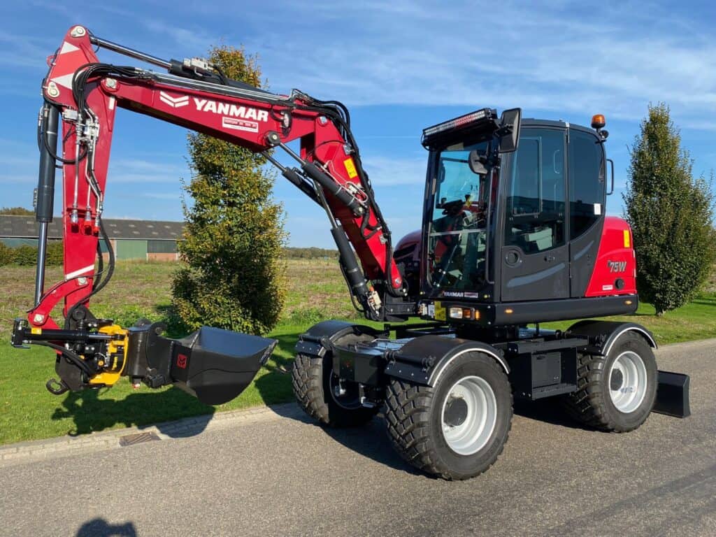 Kortere asbesteding en bouwmachine, grote tractor met graafarm op weg op landweg.