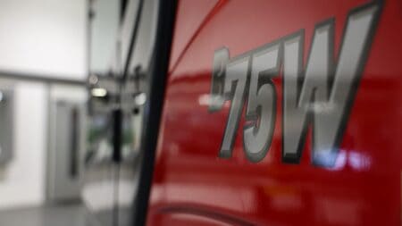 Veiligheidslicht op brandweerauto, met focus op het rode verfwerk en het logo.