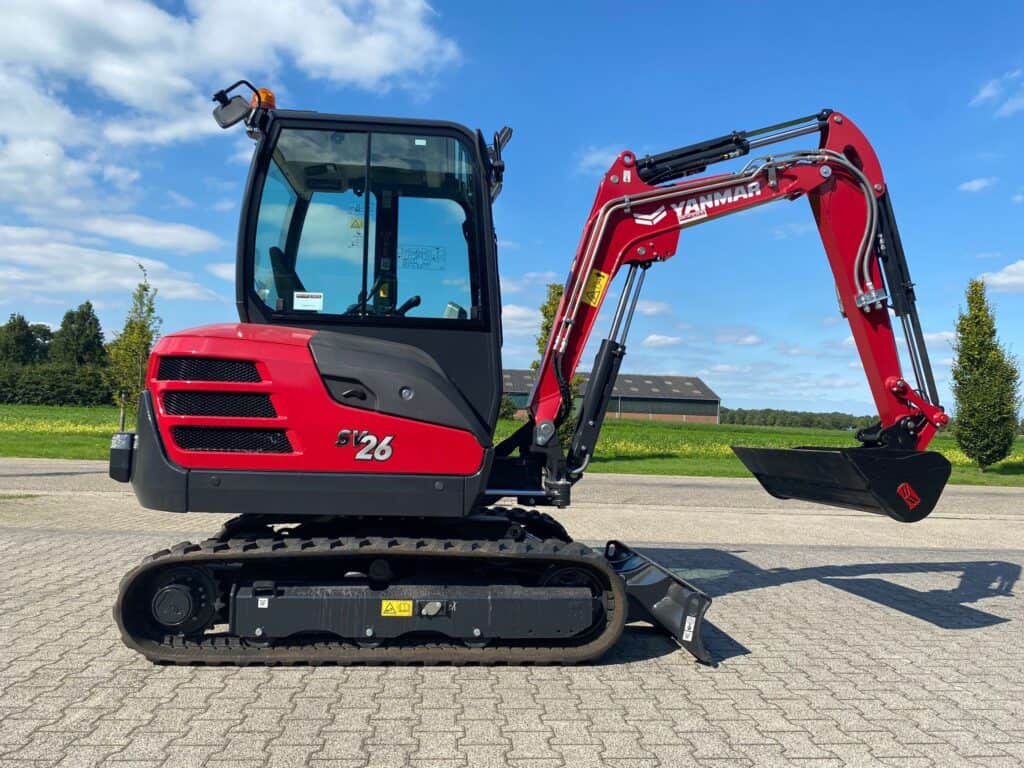 Klein steenbakker op een ondergrondse oprit met een heldere blauwe hemel en groene bomen op de achtergrond.