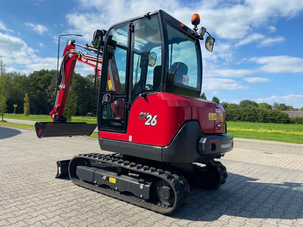 Klein minigraver op een geasfalteerde weg, geschikt voor bouw- en tuinwerkzaamheden.