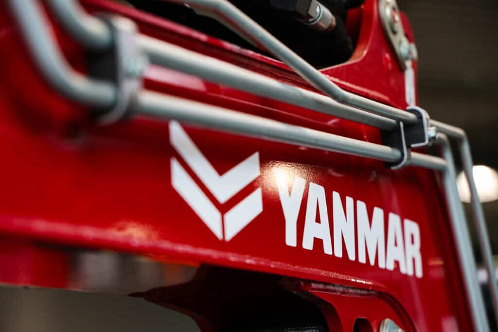 Yanmar merklogo op landbouwmachine in rood met metalen beveiliging.