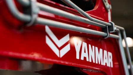 Yanmar merklogo op landbouwmachine in rood met metalen beveiliging.