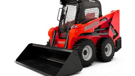 1. Mini shovelmachine van Manitou met cabine en grote banden, geschikt voor bouw en industrie.