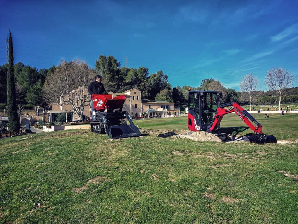 Zeer krachtige small excavator en aardeverschuifmachine voor tuin- en parkwerkzaamheden op een grasveld.