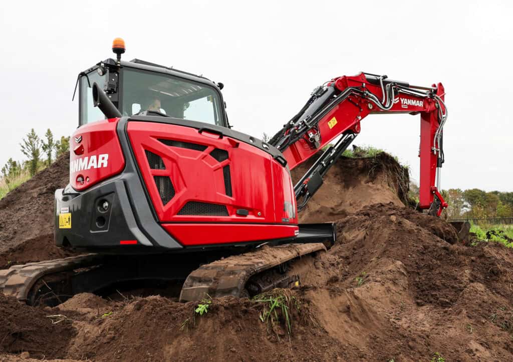 Zeer leesbare mini excavator op bouwplaats met werkzaamheden voor riolering en fundering.